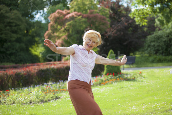 Gaiety. Delighted Playful Mature Woman with Outstretched Arms Laughing Outside Stock photo © gromovataya