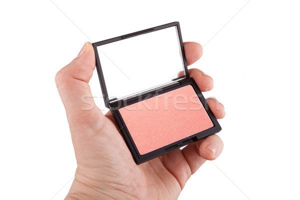 Stock photo: Female hand holding a peach and gold colored blush, isolated on 