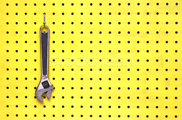 One adjustable wrench hangs from a hook on yellow pegboard Stock photo © Habman_18