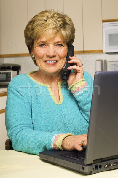Woman talks on phone while working on laptop Stock photo © Habman_18