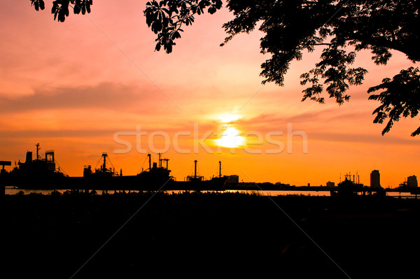 industrial ship and factory silhouetted at sunset with tree Stock photo © happydancing