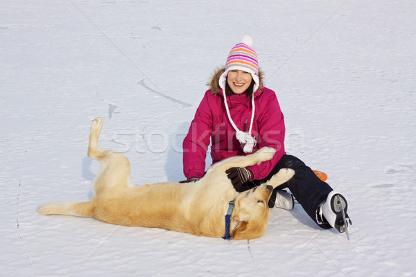 Stock photo: Girl on ice skates playing with dog