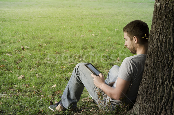 Stock photo: 	Young man reading e-book