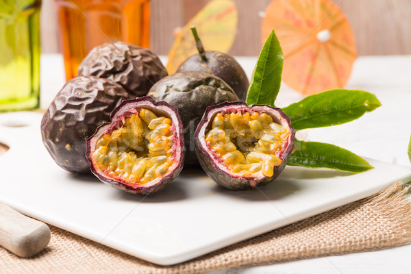 Passion fruits on white ceramic tray on wooden table background. Stock photo © homydesign