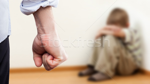 Stock photo: Angry man raised fist over wall corner sitting child boy