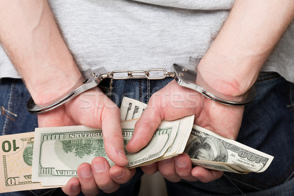 Handcuffs on hands holding money Stock photo © ia_64