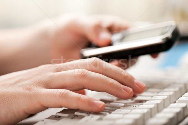 Holding phone hand typing computer keyboard Stock photo © ia_64