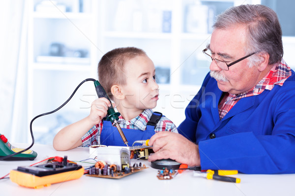 Stock photo: Grandfather teaching grandchild working with soldering iron