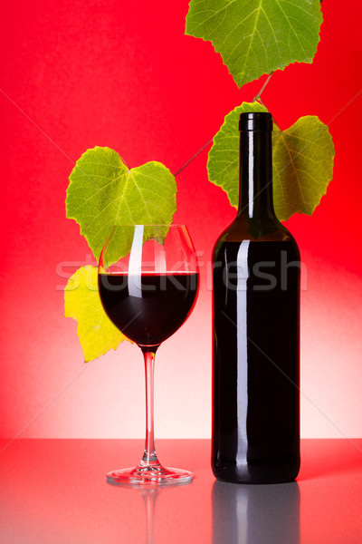 Bottle and glass of red wine with grape leaves Stock photo © icefront