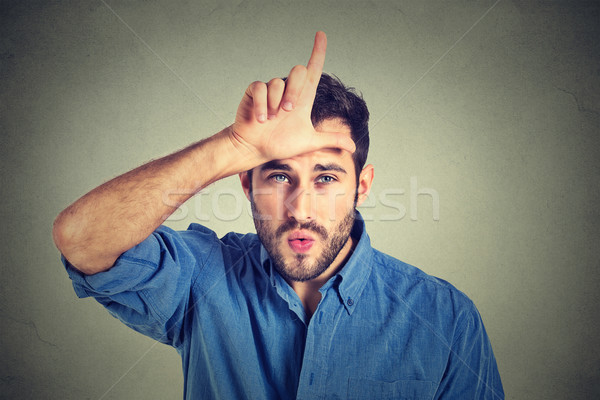  young man showing loser sign on forehead, looking at you with disgust Stock photo © ichiosea