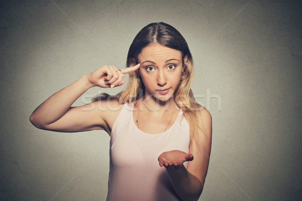 Stock photo: angry mad woman gesturing with her finger against temple asking are you crazy?