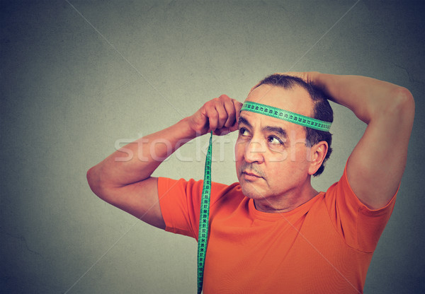 Closeup middle aged man measuring diameter of his head  Stock photo © ichiosea