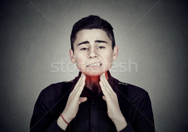 Man with sore throat irritation touching neck colored in red Stock photo © ichiosea