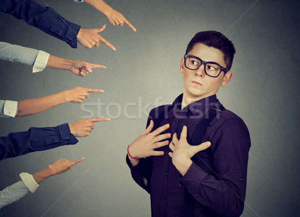 Blaming. Anxious man in denial judged by people who point fingers at him. Stock photo © ichiosea