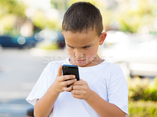 Unhappy boy looking at his smart phone Stock photo © ichiosea