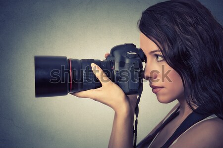 Side profile young woman taking pictures with professional camera. Studio shot   Stock photo © ichiosea