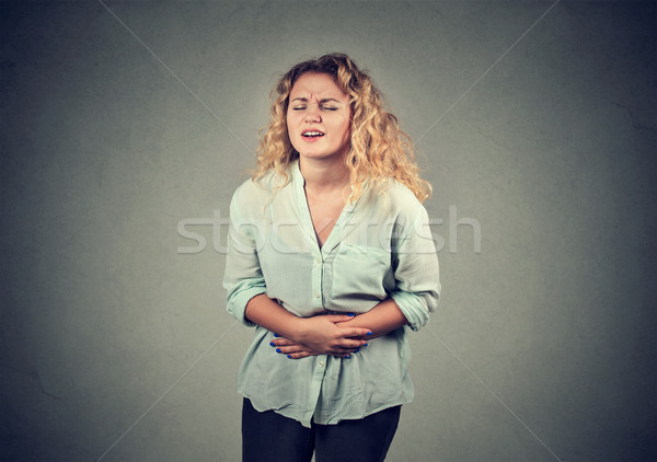 Stock photo: young woman hands on stomach having bad aches pain