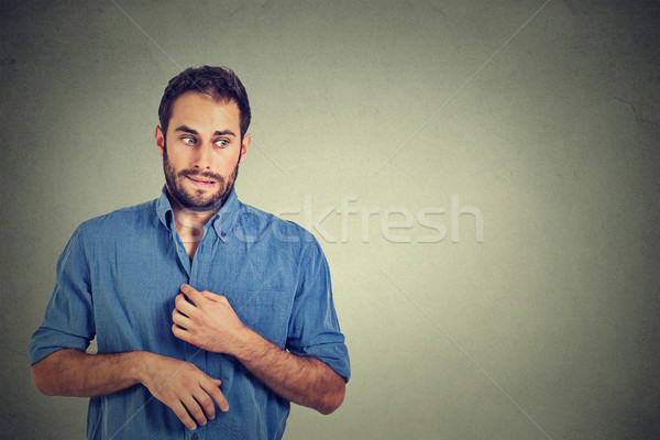 Stock photo: young man in unpleasant, awkward situation, playing nervously with hands. Embarrassment