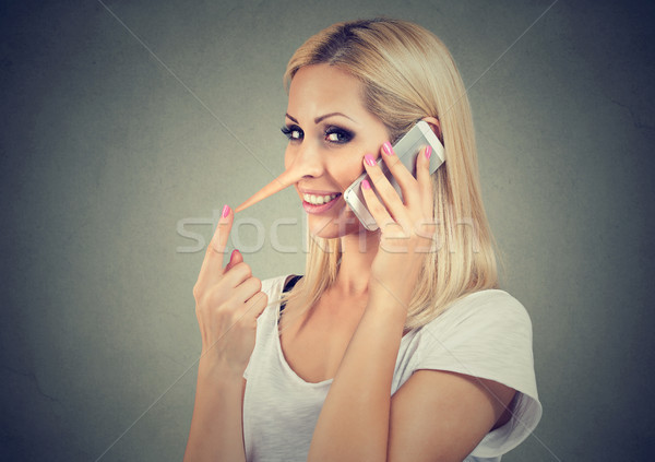 Happy blonde woman with long nose talking on mobile phone telling lies. Liar concept. Stock photo © ichiosea