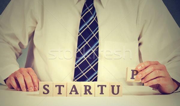 Business man hands arranging wooden cubes in a structure reading start up. Concept of entrepreneursh Stock photo © ichiosea