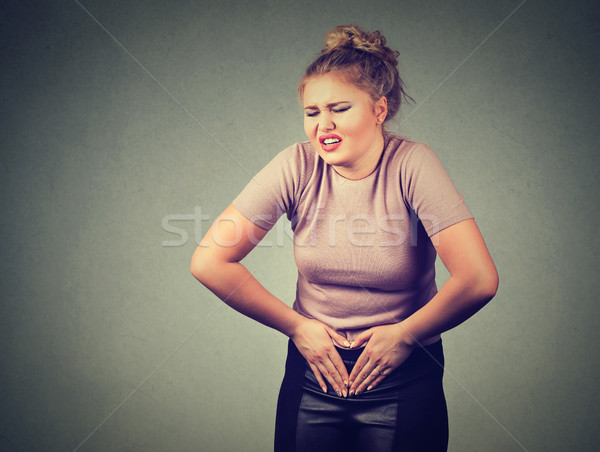 Young woman hands on stomach having bad aches pain. Food poisoning, influenza, cramps.  Stock photo © ichiosea