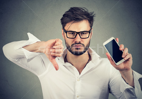Man dissatisfied with quality of gadget mobile phone  Stock photo © ichiosea