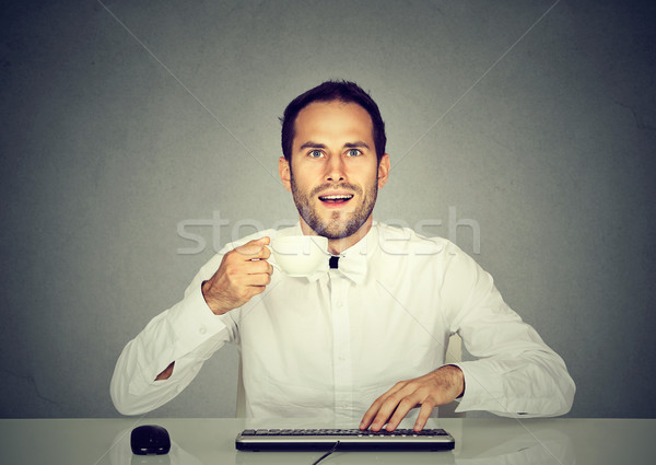 Amazed man using computer holding cup of coffee
 Stock photo © ichiosea