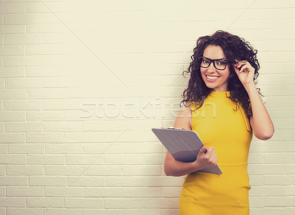 Smiling young business woman on white brick wall background. Stock photo © ichiosea