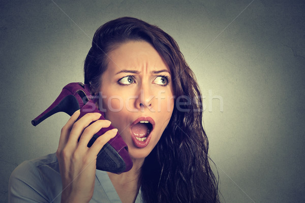 woman looking excited, surprised holding high heeled shoe in her hand as phone Stock photo © ichiosea