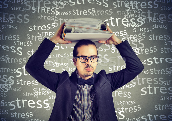 Stock photo: Stressed doomed business man standing with heavy folders on his head 