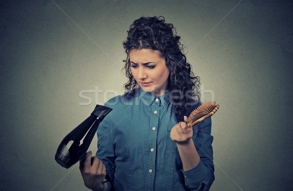 Upset young woman with hair dryer and hair brush   Stock photo © ichiosea