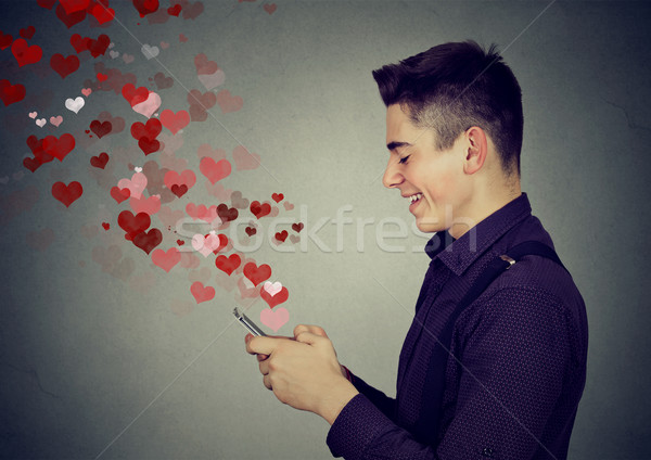 man sending love messages on mobile phone hearts flying away  Stock photo © ichiosea