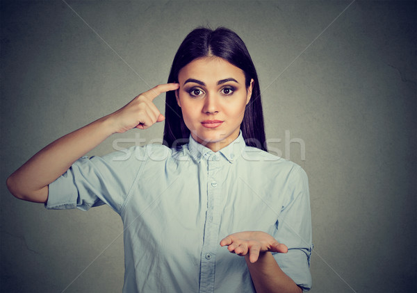 Stock photo: Angry woman gesturing with finger against temple are you crazy? 