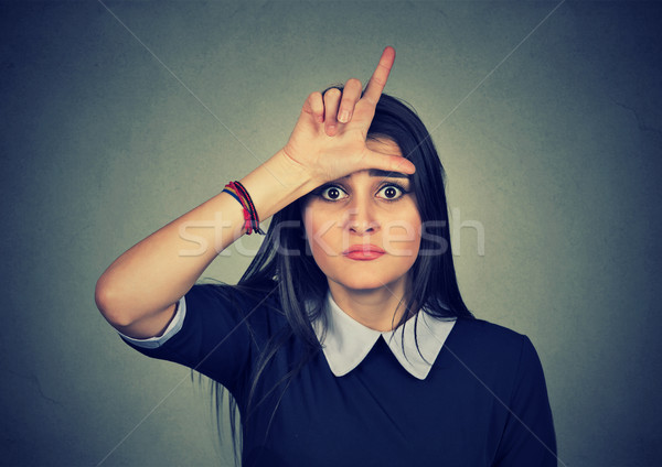 young unhappy woman giving loser sign on forehead Stock photo © ichiosea