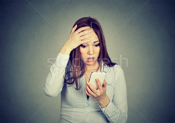 stressed woman holding cellphone worried with message she received Stock photo © ichiosea