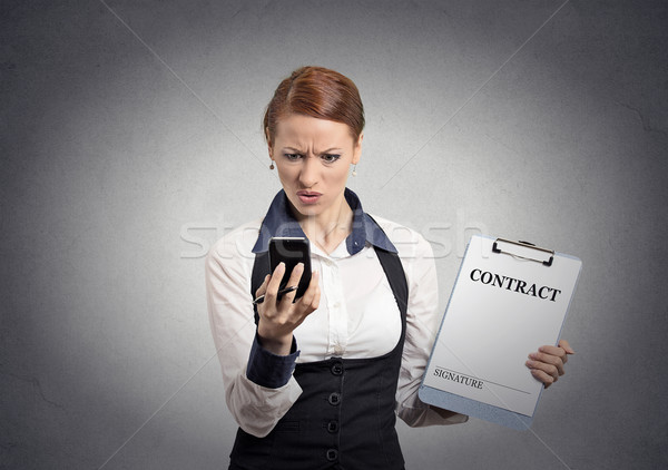skeptical businesswoman holding contract looking on smartphone Stock photo © ichiosea