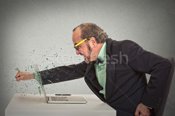 furious businessman throws a punch into computer  Stock photo © ichiosea