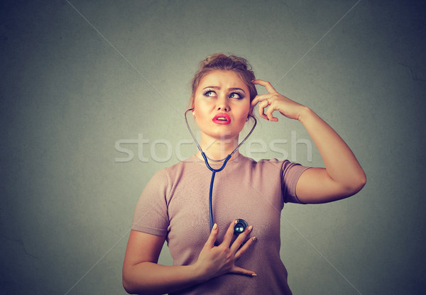Thoughtful woman listening her heart with stethoscope Stock photo © ichiosea