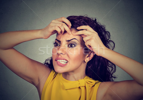 woman looking in a mirror squeezing acne or blackhead on her face  Stock photo © ichiosea