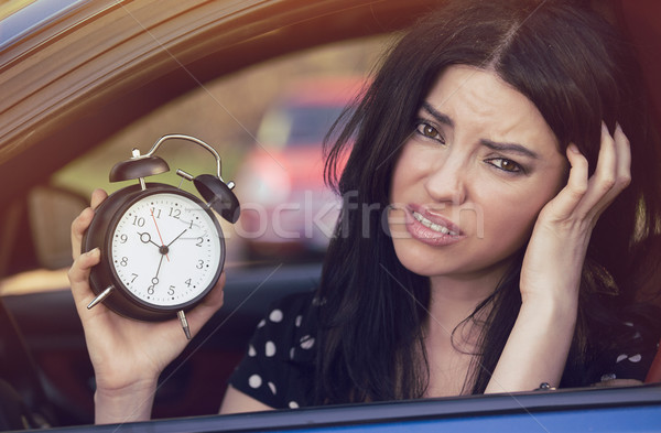 Worried woman inside car showing alarm clock running late to work Stock photo © ichiosea