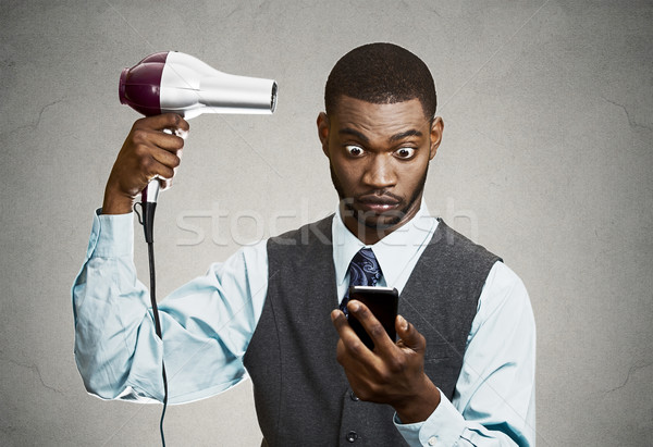 Stock photo: Businessman texting while using haidryer  