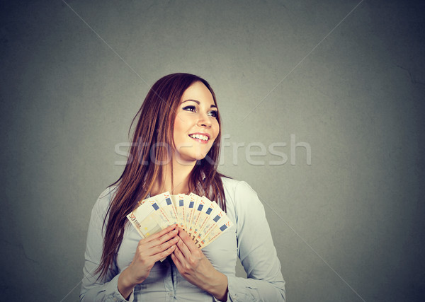 Stock photo: Woman holding money euro banknotes dreaming how to spend 