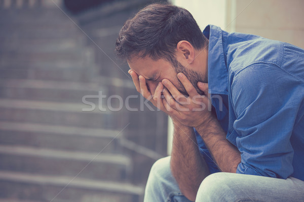 stressed sad young crying man sitting outside holding head with hands  Stock photo © ichiosea