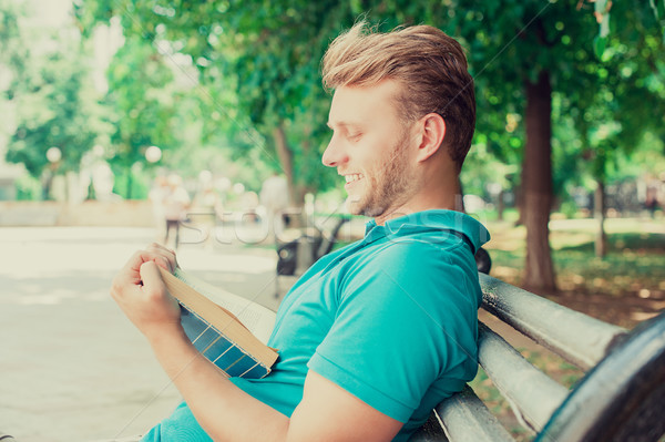 Happy smiling man reading a book funny story in a park on summer sunny day  Stock photo © ichiosea