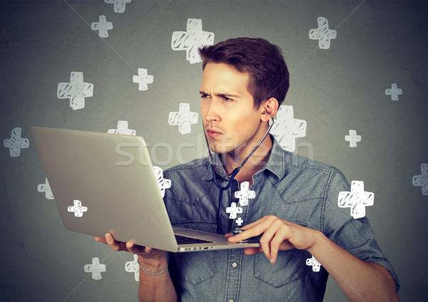 Man listening computer with stethoscope looking at pc laptop.  Stock photo © ichiosea