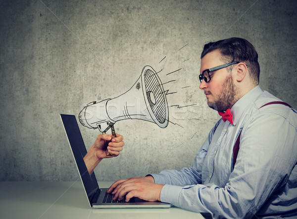man sitting at table working on computer screaming with a megaphone poking out from a laptop screen Stock photo © ichiosea