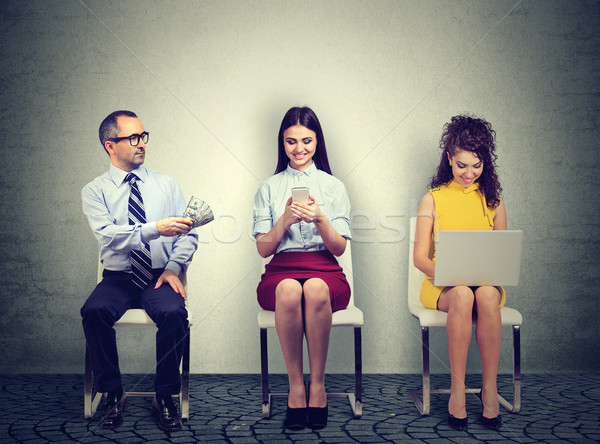 Mature business man offering money to a young woman using mobile phone sitting next to an employee w Stock photo © ichiosea