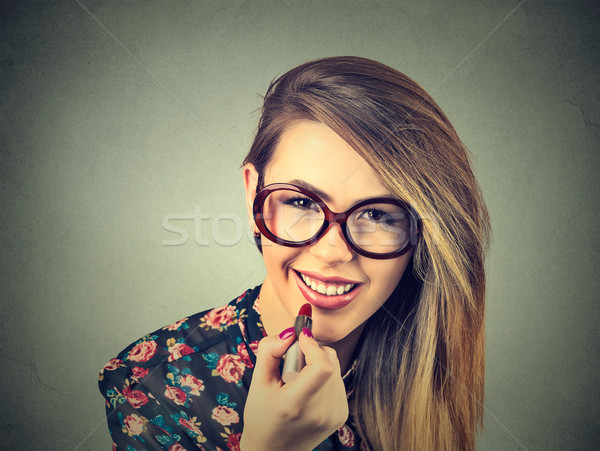 Portrait of young woman applying lipstick isolated on gray wall background   Stock photo © ichiosea
