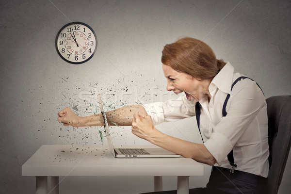Furious businesswoman throws a punch into computer, screaming Stock photo © ichiosea