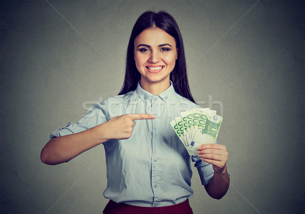 Stock photo: Money. Business woman looking at camera pointing at cash 